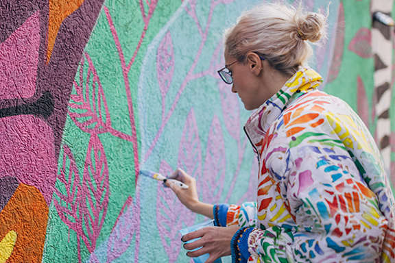 A woman painting a mural on a wall.