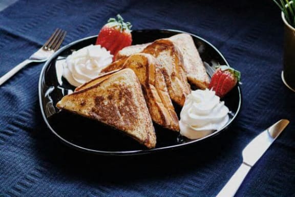 a plate toast with whipped cream and strawberries