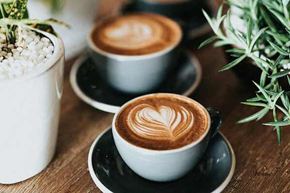 Two cups of coffee with latte art on a wooden table.