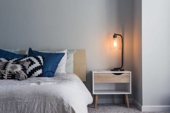 a bedroom with a bed and a nightstand with a lamp on it