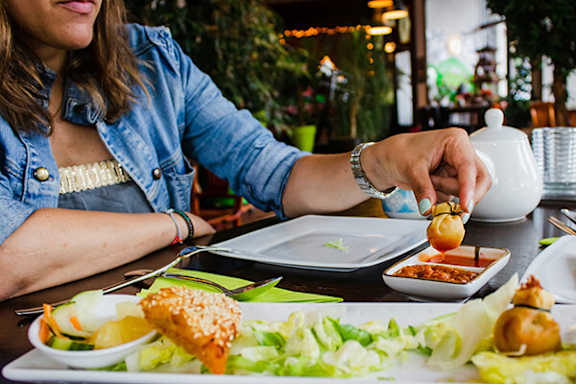 A woman is pouring sauce on a dish at a restaurant.