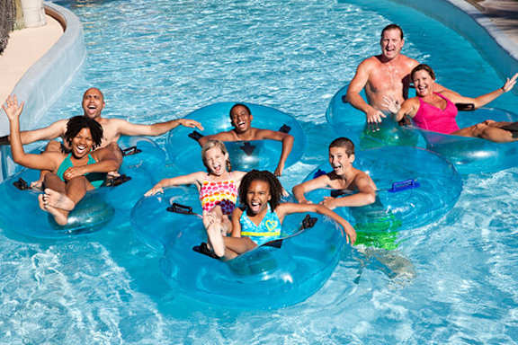 People are floating on blue inner tubes in a pool.