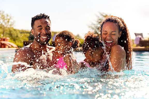 A family of four is enjoying a swim in a pool.