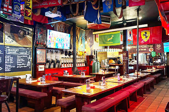 A restaurant with red booths and a variety of flags hanging from the ceiling.