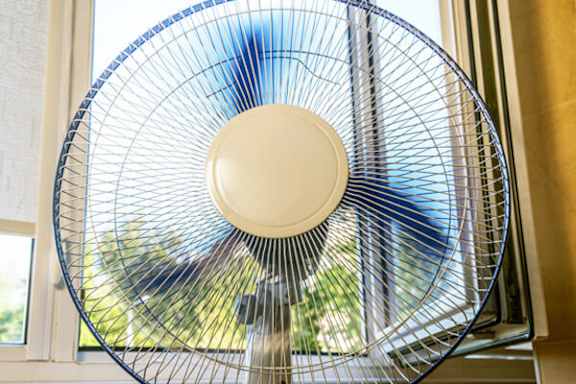 A fan is on a windowsill.