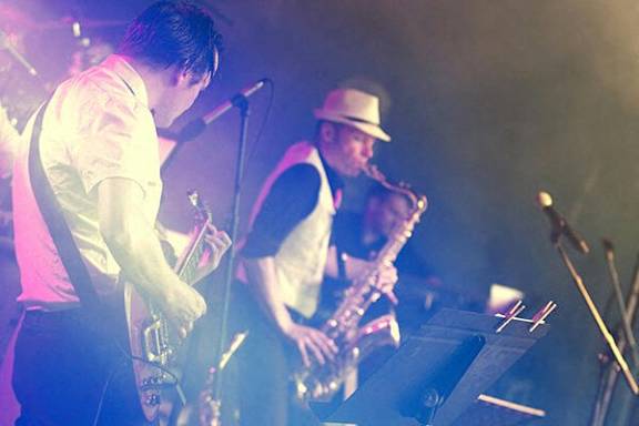 A man in a hat is playing the saxophone on stage.