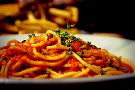 A plate of spaghetti with tomato sauce and garnished with parsley.