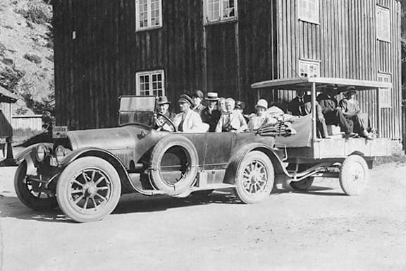 A black and white photo of a vintage car with people sitting in the front and back.