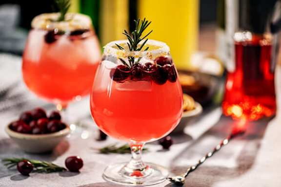Two glasses of pink drink with a sprig of rosemary on top.