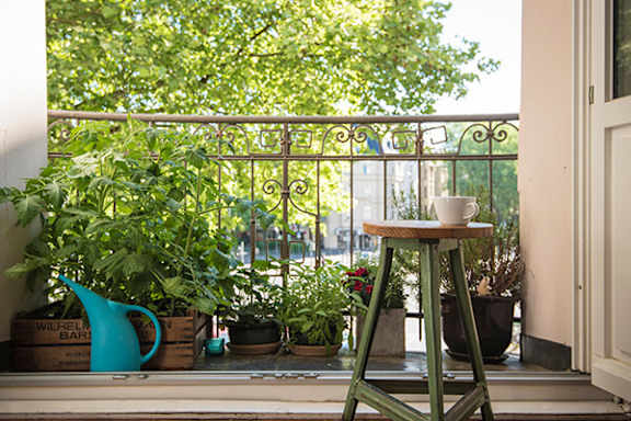 A table with a cup on it sits on a balcony.