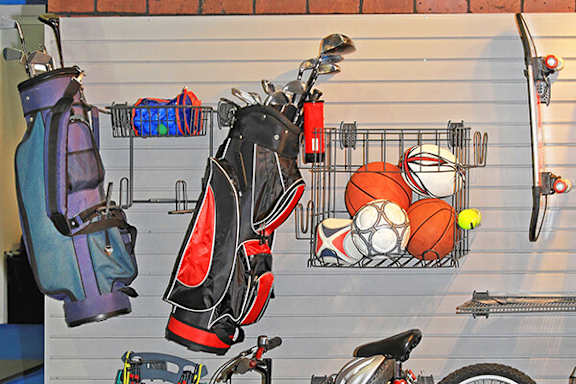 A wall-mounted rack holds golf clubs and sports balls.