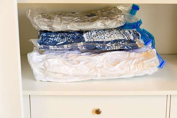 A white cabinet drawer is full of plastic-wrapped items.
