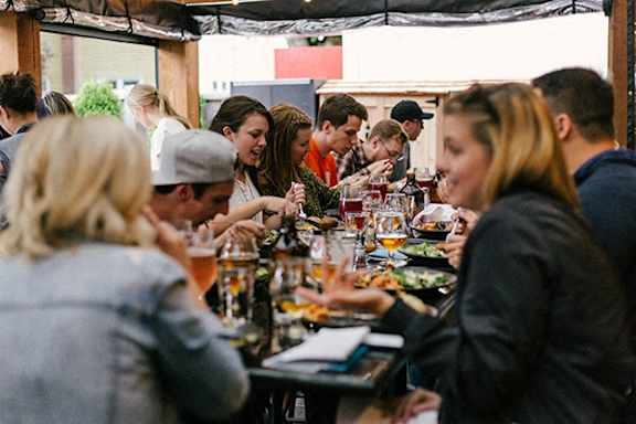 A group of people are sitting at a long table, eating and drinking.