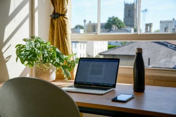 a laptop computer sitting on a table next to a window
