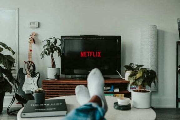 a person with their feet on a table in front of a television