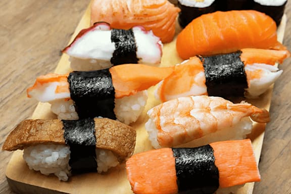 A wooden board with assorted sushi, including nigiri and sushi rolls.