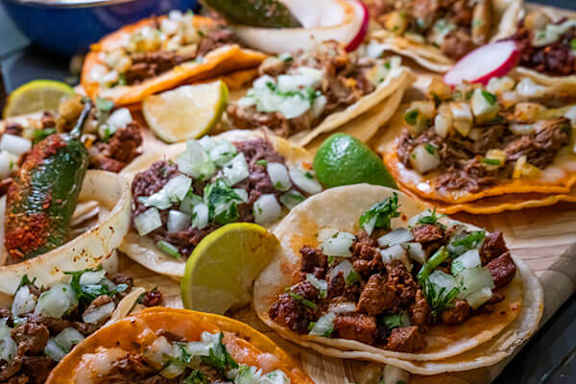 A close up of a plate of tacos with meat, onions, and lime.