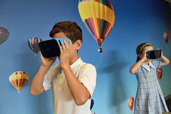 a boy and a girl are taking a photo with hot air balloons in the background