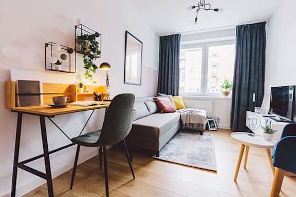 A modern living room with a wooden desk and a black chair.