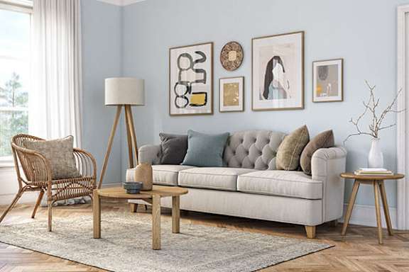 A living room with a grey couch, a wooden floor, and a white chair.