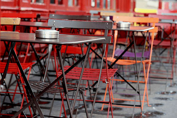Empty tables and chairs are arranged in a row.
