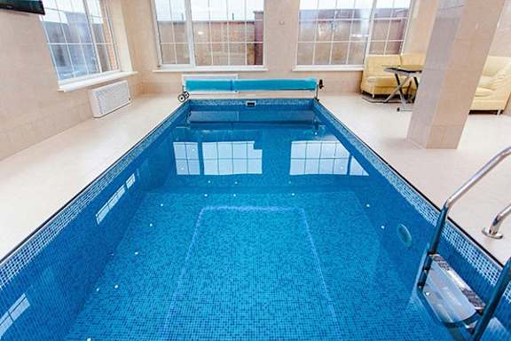 a large swimming pool in a house with a blue tiled floor