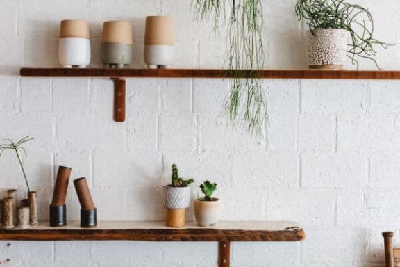 a shelf with pots and plants on a white wall