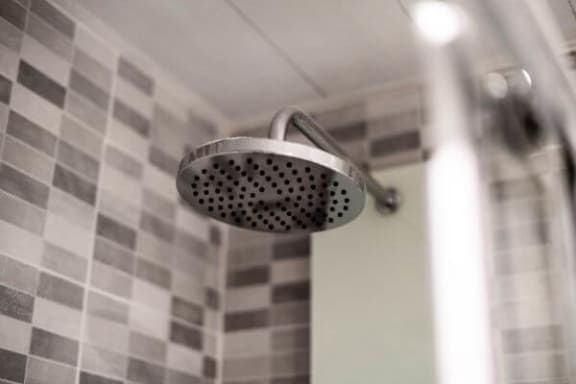 a shower head in a bathroom with black and white tiles