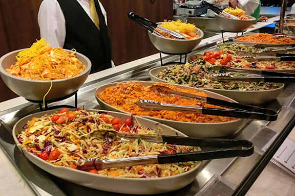 A buffet with a variety of foods including pasta and salad.