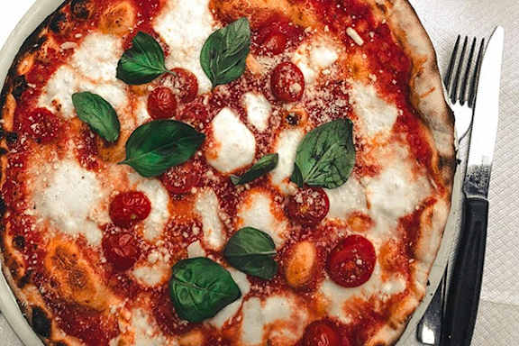 a pizza with pepperoni and basil on a plate with a fork