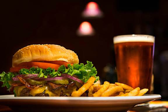 A burger and fries on a plate with a glass of beer.