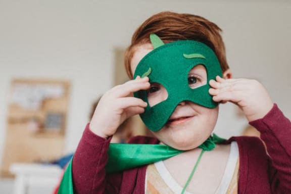 a young girl is wearing a green mask