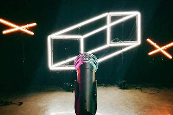 A microphone is in front of a neon sign.