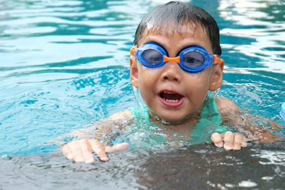 a young boy in a swimming pool wearing goggles