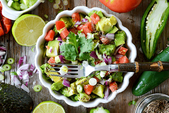 A bowl of fresh salad with a fork in it.