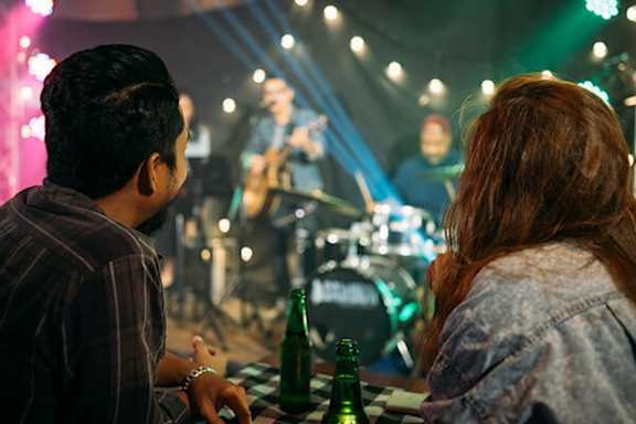 A man and a woman are sitting at a table in front of a band performing on stage.