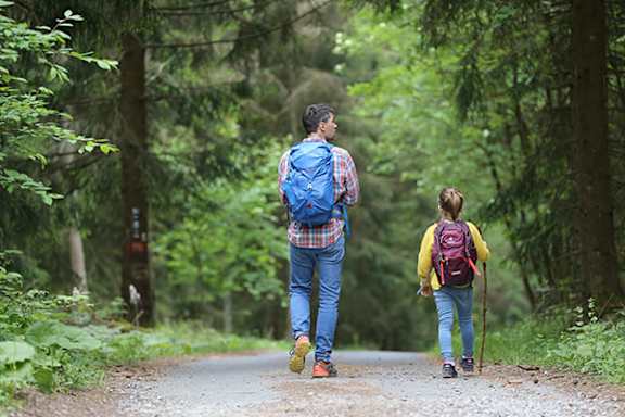 A man and a woman are walking on a path in the woods.