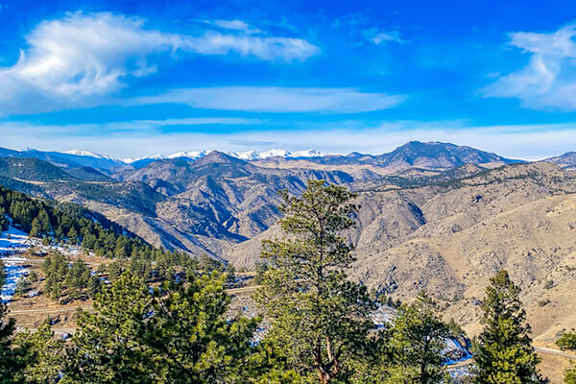 A mountain range with snow on the peaks and trees in the foreground.