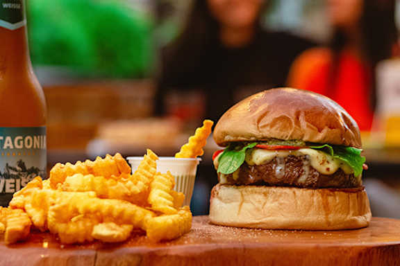 A burger and fries are on a wooden board.