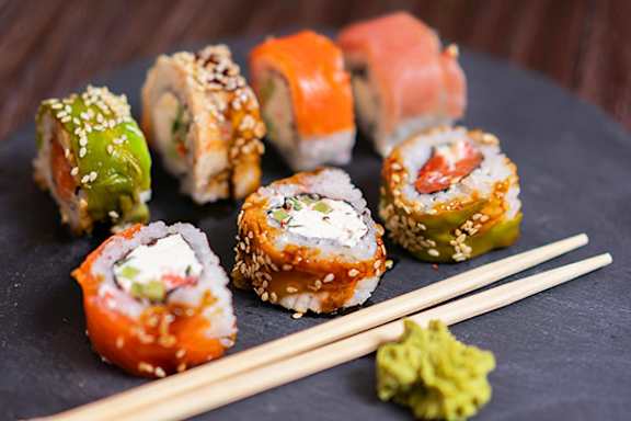 A plate of sushi with chopsticks and wasabi.