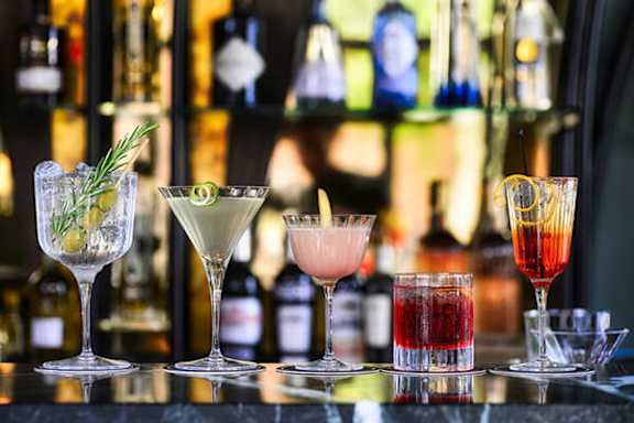 Four cocktails are lined up on a bar counter.