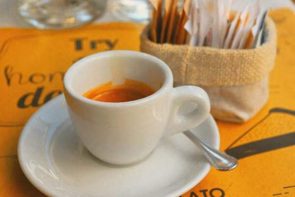 A white cup of tea with a spoon on a saucer.