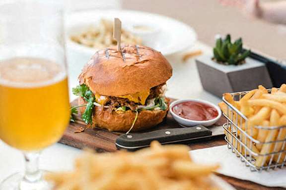 A burger and fries on a table with a glass of beer.