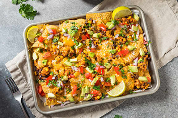 A tray of nachos topped with cheese, meat, and vegetables.