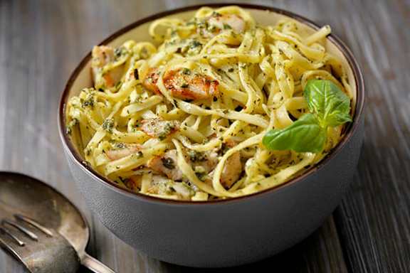 A bowl of pasta with shrimp and a garnish of basil.