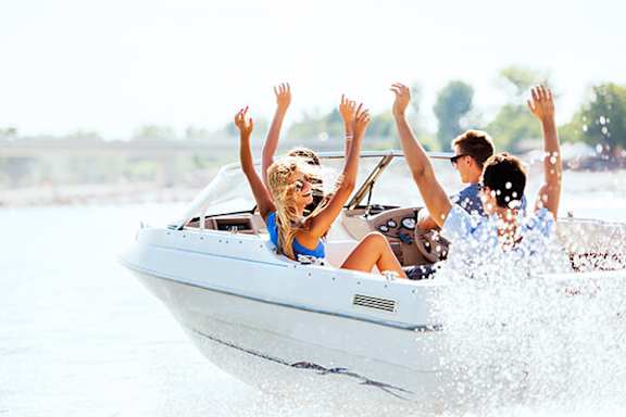A group of people are riding on a speedboat with their arms raised in excitement.