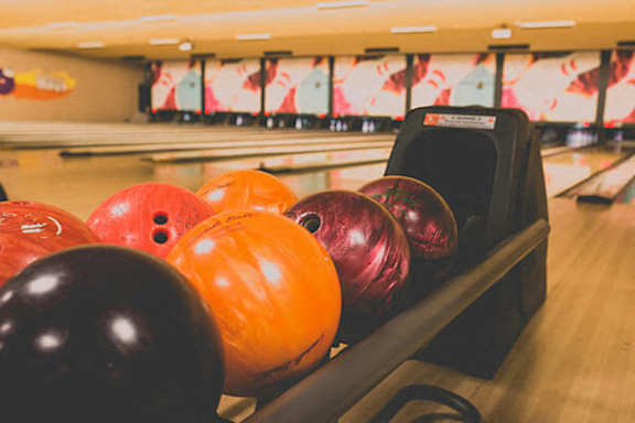 A row of bowling balls are lined up on a lane.