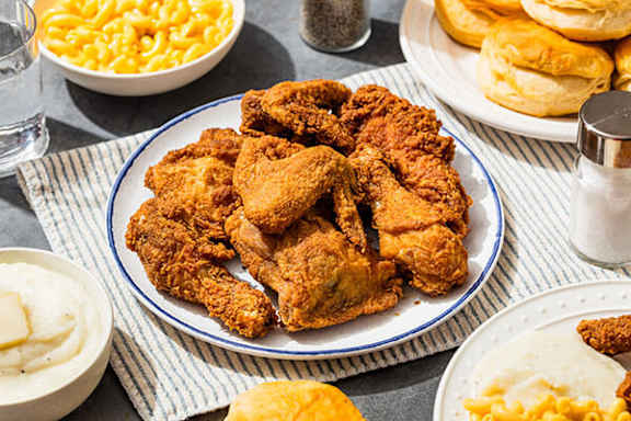 Fried chicken on a plate with sides of macaroni and cheese and biscuits.