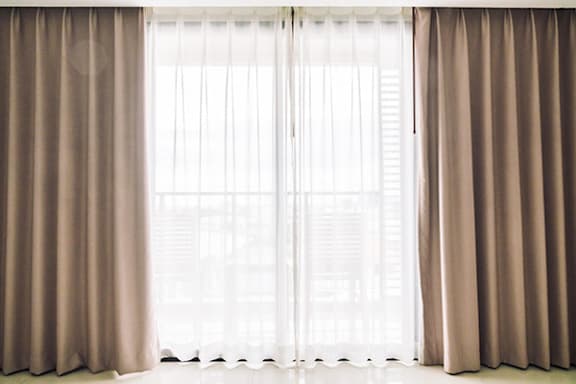 A window with beige curtains and a white interior.