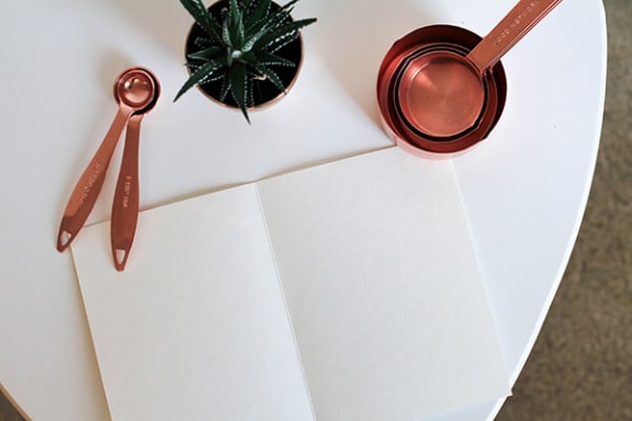 a piece of paper with a pen on it next to a succulent and a measuring spoon